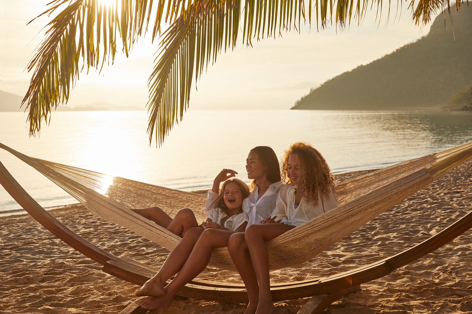 Family in hammock on Catseye Beach on Hamilton Island in the heart of Australia's Great Barrier Reef.